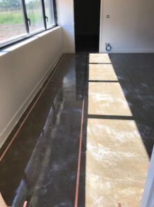 Plan de travail ou sol d’atelier en cours, prêt pour pose d’un revêtement antistatique définition et norme ESD, noir brillant.