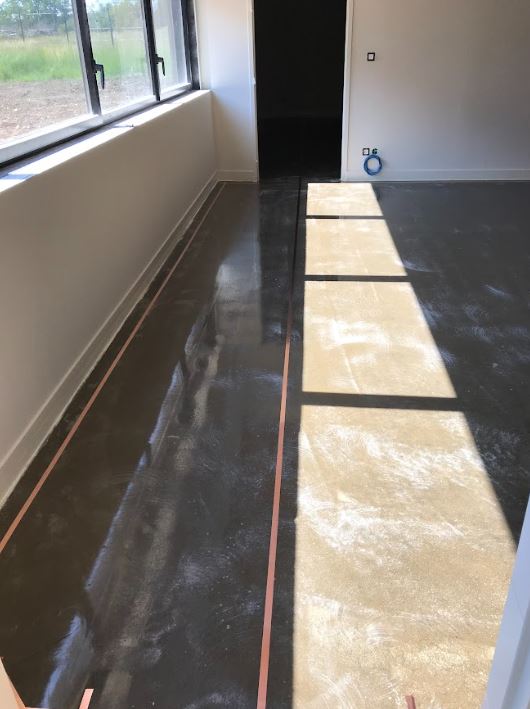 Plan de travail ou sol d’atelier en cours, prêt pour pose d’un revêtement antistatique définition et norme ESD, noir brillant.